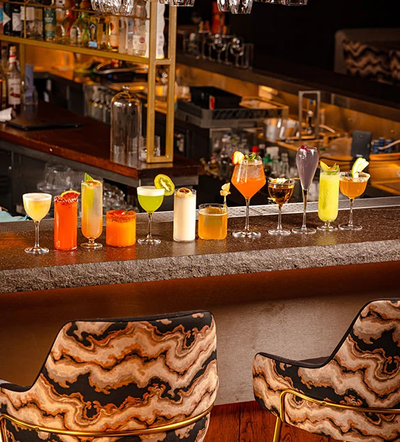 UYARE bar counter with colorful cocktails and patterned lounge chairs