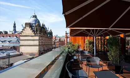 Rooftop bar terrace with outdoor seating and views of historic Leeds buildings.