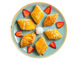 Triangular pastries arranged on a plate with dip and strawberry garnish
