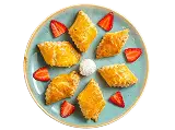 Triangular pastries arranged on a plate with dip and strawberry garnish