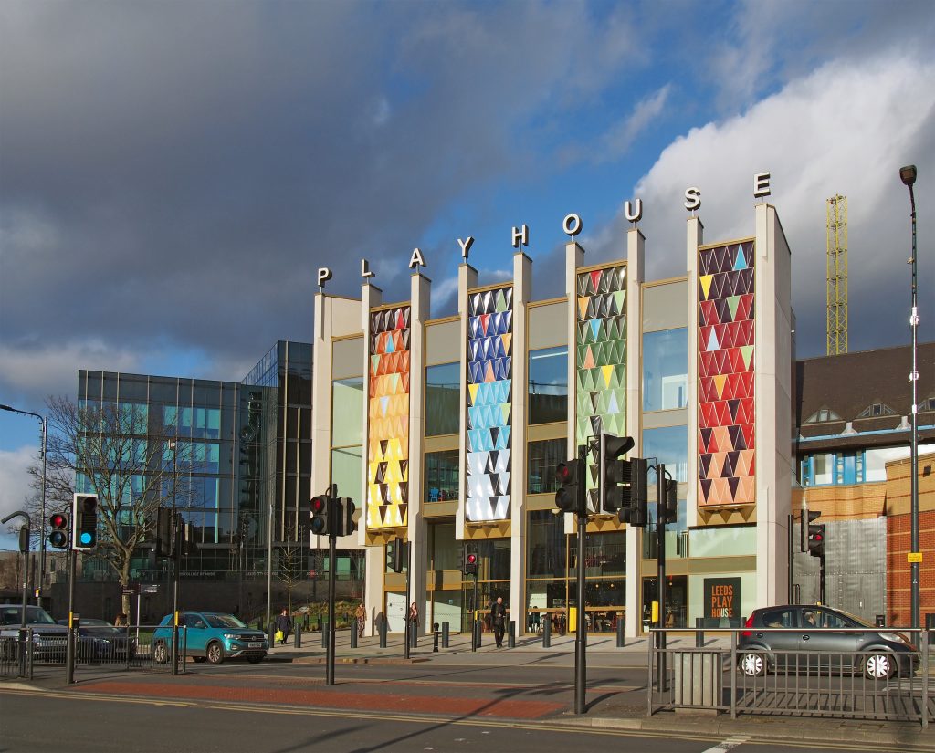 The colourful, panelled exterior of Leeds Playhouse, featuring the venue's signature multicoloured facade against a partly cloudy sky.