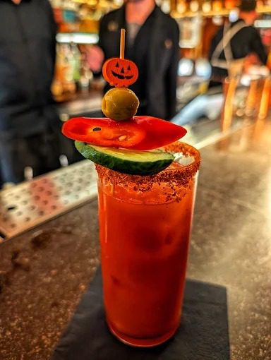 Curry Mary cocktail at Uyare, made with curry vodka, mango pickle and tomato, garnished with cucumber and red pepper.