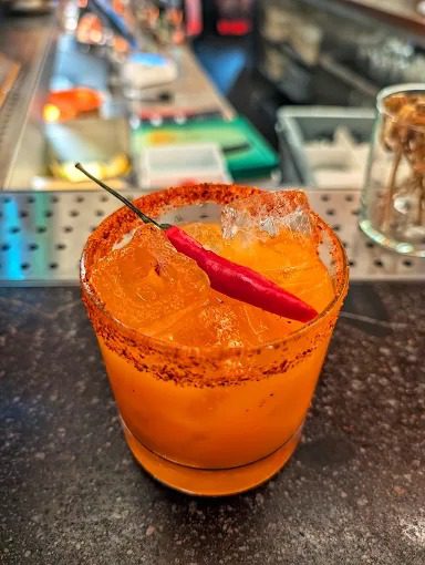 Mango cocktail with a chilli-spiced rim and fresh red chilli garnish, one of Uyare's spice-led signature serves.