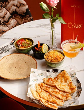UYARE table setting with mezze bowls, flatbread, cocktail, and a rose